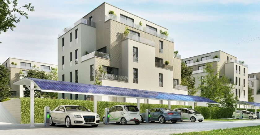Sähköautojen latausasema taloyhtiön parkkipaikalla aurinkopaneelikatoksen alla.